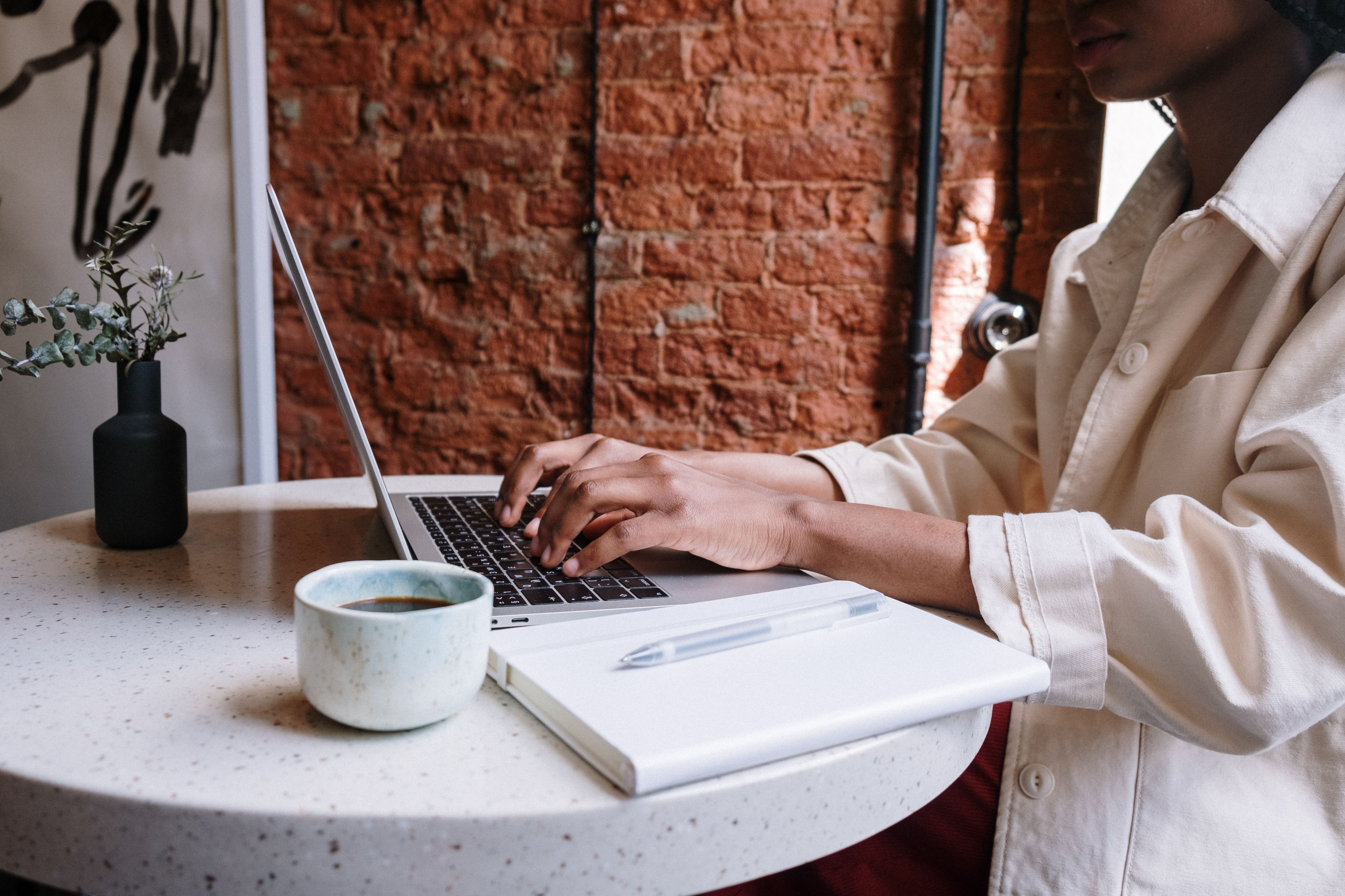 Woman writing and working on a laptop with coffee in a cozy workspace, representing blog content creation.